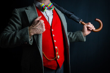 Portrait of Dapper Gentleman in Red Waistcoat Holding Umbrella Over Shoulder. Vintage Style of Eccentric English Gentleman.