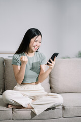 Obraz premium Overjoyed charming excited asian business woman worker using smartphone and laptop working in office, feeling happy.