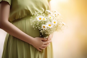 Close-up on the belly of a pregnant woman, wearing a long green dress, holding a bouquet of daisy flowers outdoors, new life concept