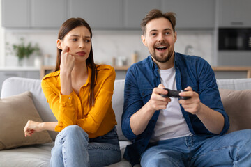 Man plays video game while woman looks on skeptically