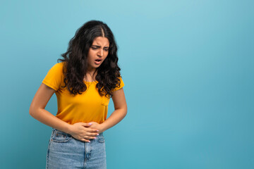 Young indian woman with abdominal pain, copy space