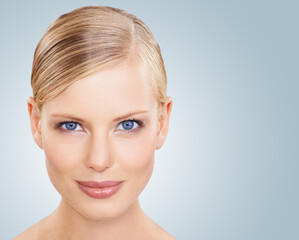 Fototapeta premium Portrait, skincare and woman with cosmetics, wellness and beauty on a blue studio background. Face, person or model with shine and makeup with grooming or dermatology with aesthetic, mockup or facial