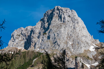 Panoramic view of majestic steep mountain peak Foelzstein in untamed Hochschwab mountain region, Styria, Austria. Scenic hiking trail on sunny day in remote Austrian Alps. Wanderlust in alpine summer
