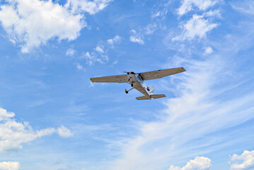 Fototapeta na wymiar Single engine ultralight plane flying in the blue sky with white clouds 
