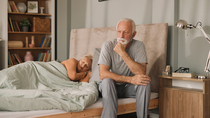 Senior man sitting on bed in his bedroom