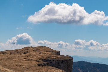 Scenic hiking trail along idyllic alpine meadow to summit cross of Foelzstein in wild Hochschwab massif, Styria, Austria. Wanderlust in remote Austrian Alps on sunny spring day. Achievement of goal