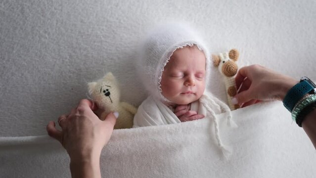 Solicitous Mom Puts Newborn Baby To Bed Adding A Knitted Toy