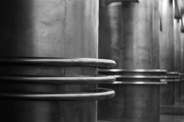 A pattern of round metal columns going off into the distance - black and white film photograph 