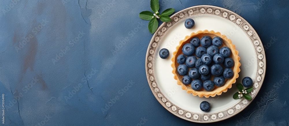 Sticker Top view on blueberry mini tart served on blue ceramic plate over gray textile napkin Top view Square image. Creative Banner. Copyspace image