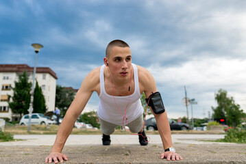Athletic man doing push-up on a road at sunset.