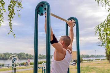 Man doing pull ups in the park.Young athletes train at the gym in the open.