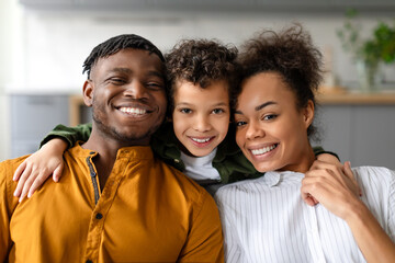 Portrait of cheerful black family of three embracing and smiling