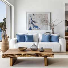 Fototapeta na wymiar Live edge accent coffee table near white sofa with blue pillows against wall with big poster frame. Coastal home interior design of modern living room