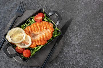 Grilled salmon steak with arugula salad, tomatoes and shallots. The concept of healthy eating,...