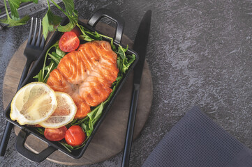 Grilled salmon steak with arugula salad, tomatoes and shallots. The concept of healthy eating, diet, low calorie. Top view, flat lay