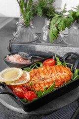 Grilled salmon steak with arugula salad, tomatoes and shallots. The concept of healthy eating, diet, low calorie