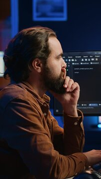 Programmer doing web development during remote job shift in neon lit home office, finishing coding project. IT specialist sitting at computer desk, working on desktop PC, camera A
