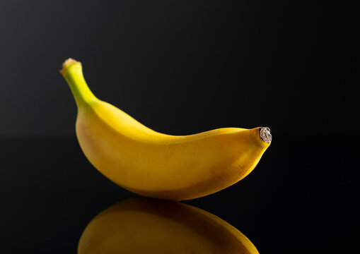 Banana on a black reflective background.
