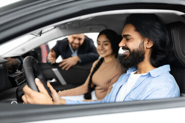 Excited young indian couple sitting inside brand new car