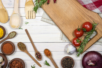 Fresh vegetables and spices, cutting board on white wooden background. Free space.