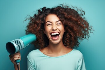 A woman with curly hair holding a blow dryer. Perfect for beauty and hairstyling related content - obrazy, fototapety, plakaty