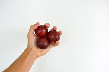 mão de homem segurando ameixas vermelhas 