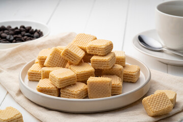 Wafer filled with milk cream flavored in white plate with cup coffee background