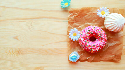 White zefir and pink donut on wooden table, top view. Copy space for the text