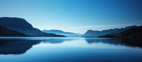 Tranquil body of water with reflections of nature and clear blue sky in a peaceful scenic landscape