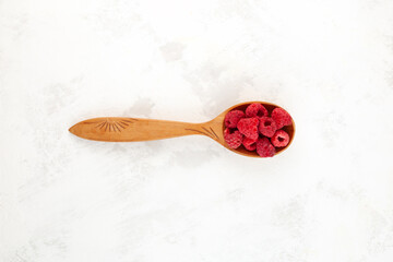 Dried freeze dried raspberries in wooden spoon on the table, top view. Dehydrated raspberry berries. Clever Storage healthy food