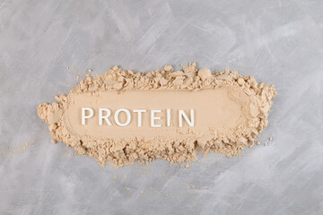 Heap of Pure Whey Protein Powder on grey textured background, top view. Inscription PROTEIN. Food...