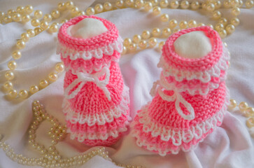 Pink knitted booties on light background with beads