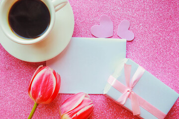 Flat lay photo with coffee cup, gift box and red tulips on pink background. Beautiful Mother's Day, Women's Day or Valentine greeting card. Mother's Day mockup greeting card