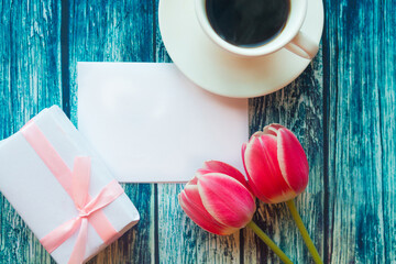 Flat lay photo with coffee cup, gift box and red tulips on wooden background. Beautiful Mother's...