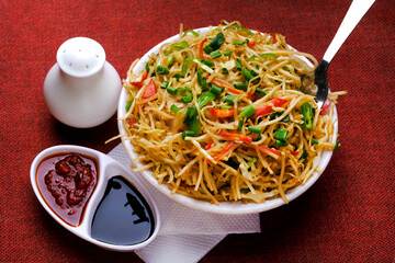 Schezwan Noodles or vegetable Hakka Noodles, or chow mein is a popular Indo-Chinese recipes, served in a bowl, Stir-fried noodles. - obrazy, fototapety, plakaty