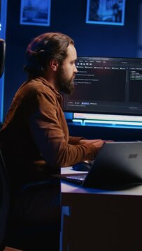 Overworked developer complaining while typing difficult code in home office, developing software application. IT expert groaning while solving coding project tasks, suffering from burnout, camera B