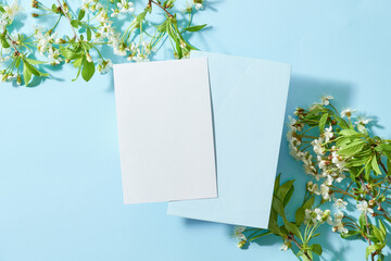 Mockup white greeting card and envelope with spring flowers on a blue background