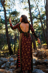 Young beautiful woman dancing in the forest with her hand raised.