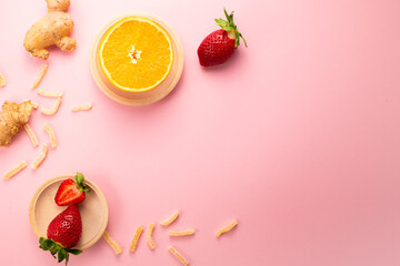Ginger in sugar, strawberries and orange on pink background. Gourmet oriental sweets. Flat lay. Copy space