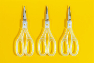 three set of scissors in plastic on yellow background