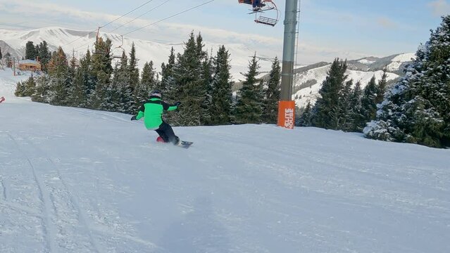 Athlete with a hard snowboard for slalom in a ski resort. Snowboarder is a race slalom. Snowboarding on the hill of snow on ski slope on sunny winter day with clear blue sky.