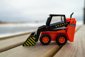 Toy forklift with striped bucket, rolling on black wheels