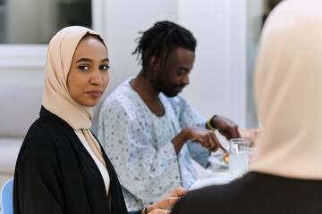A traditional and diverse Muslim family comes together to share a delicious iftar meal during the...