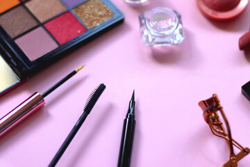 Various colorful make up products on pastel pink background. Selective focus.