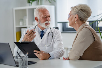 A specialist doctor consults with an elderly female patient in his office