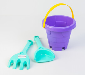 Children's toy bucket with shovels for playing in the sand on a white background.
