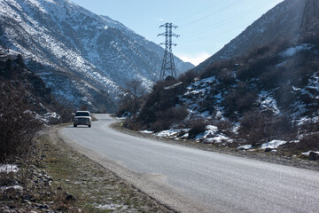 asphalt road with car leading towards snow mountains - 735277936