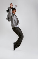 Kid, fashion and dance with energy in studio with hoodie in streetwear on grey background. African, child and cool teenager or dancer with casual style, clothes and balance on shoes in mockup - obrazy, fototapety, plakaty