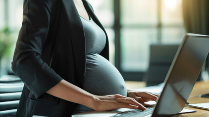 pregnant woman in a professional setting, working on a laptop.