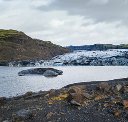 Solheimajokull picturesque glacier in southern Iceland. The tongue of this glacier slides from the volcano Katla. Beautiful glacial lagoon with blocks of ice and surrounding mountains.